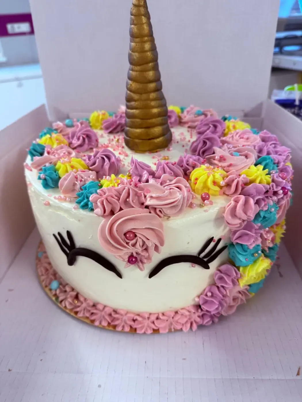 Torta unicorno con corno dorato e roselline di crema colorate